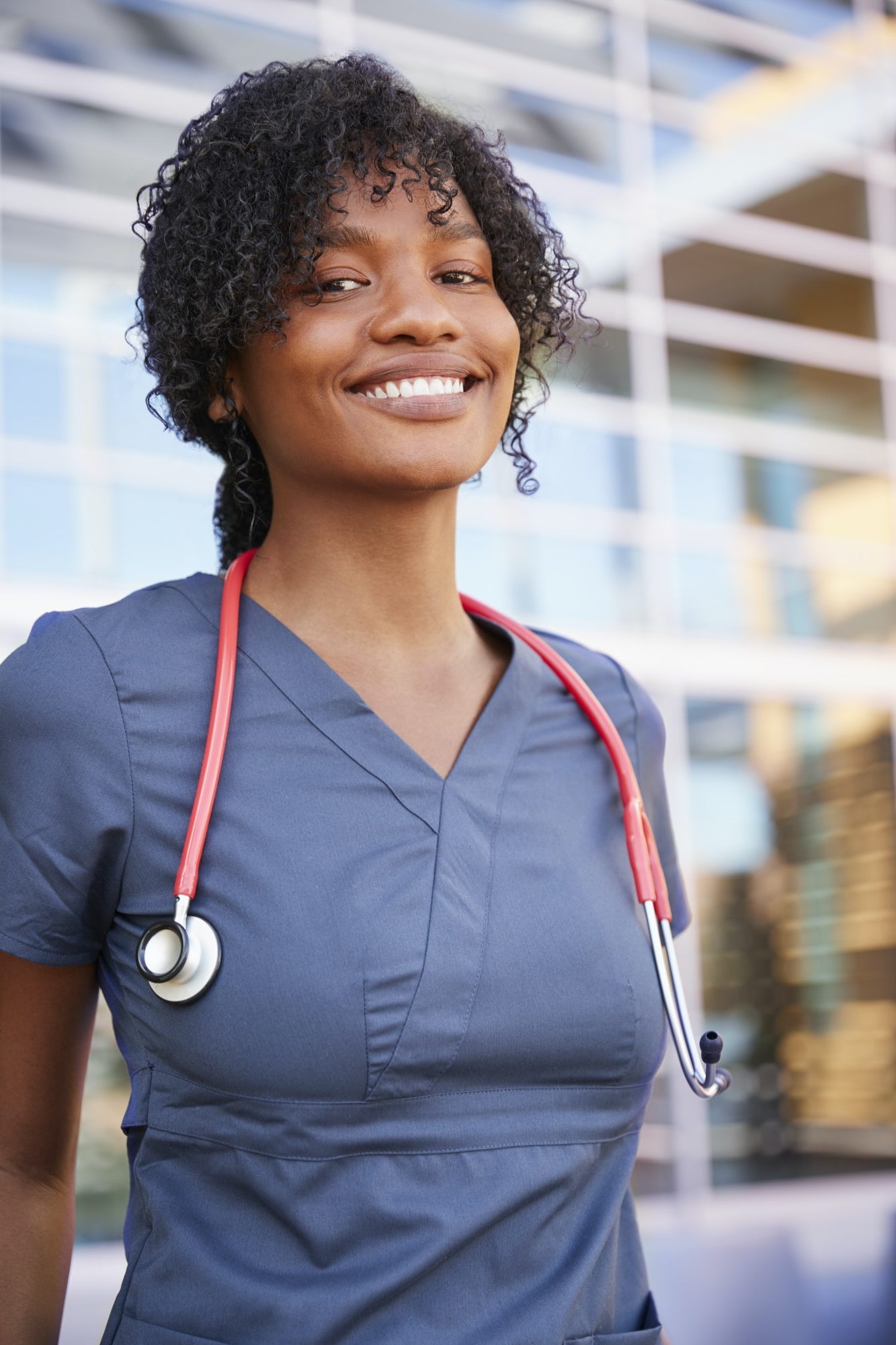 Smiling black female healthcare worker outdoors, vertical